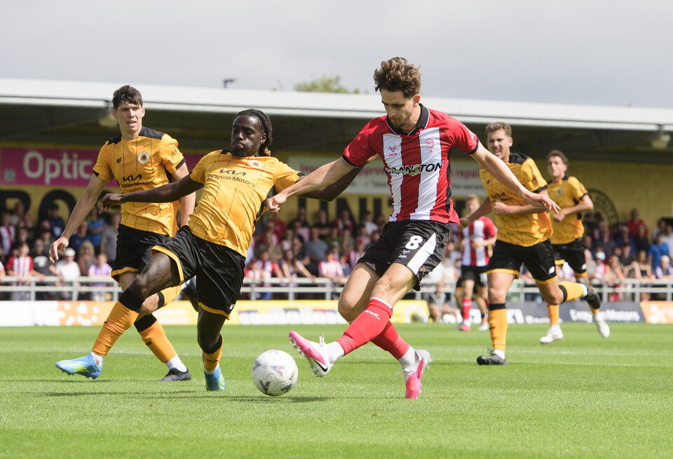 Tom Bayliss scores for Lincoln City, kicking the ball with his left foot.