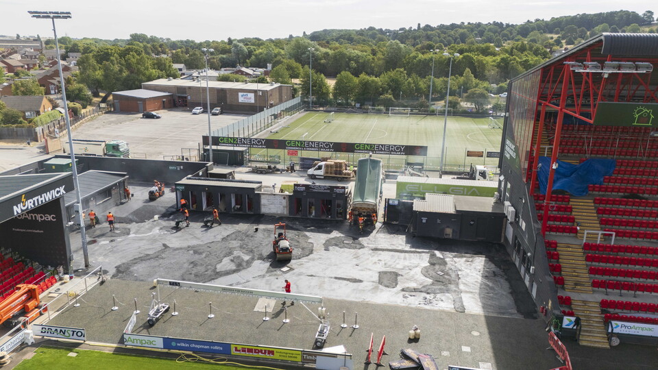 An aerial image of workers putting a new surface down inside a football stadium