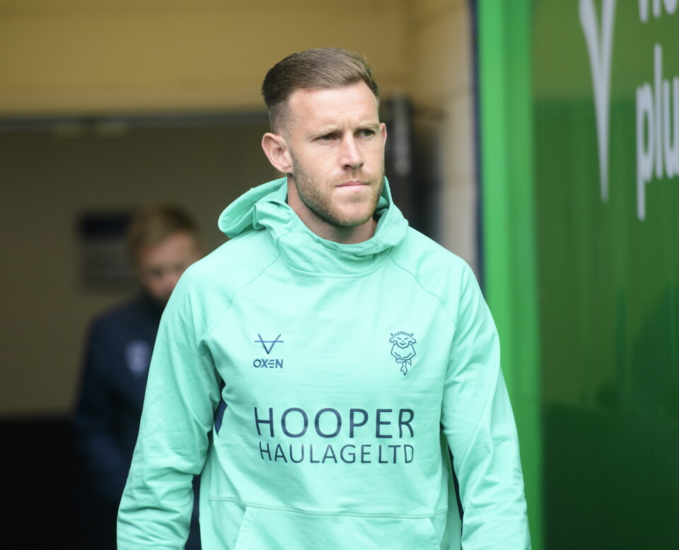 Callum Edler walks out of the tunnel. He is wearing a green hody.