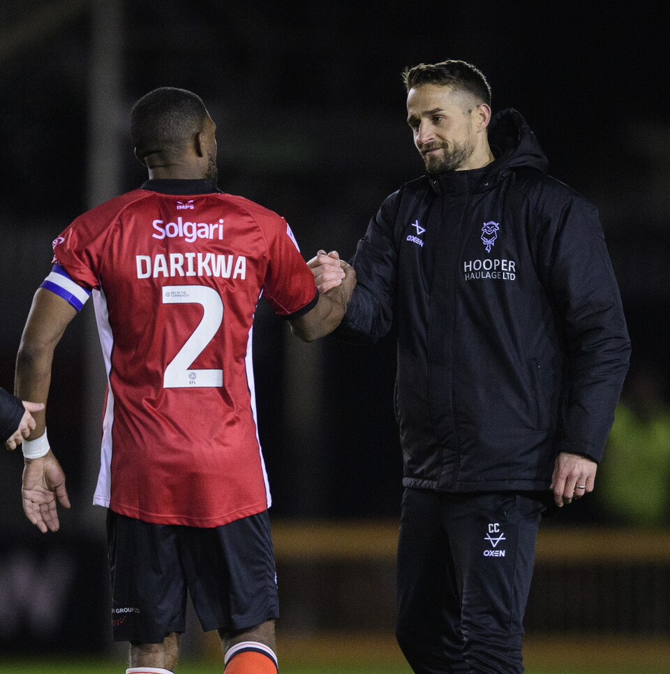Tendayi Darikwa and Chris Cohen shake hands on a football pitch. It is dark and they are illuminated by floodlights.
