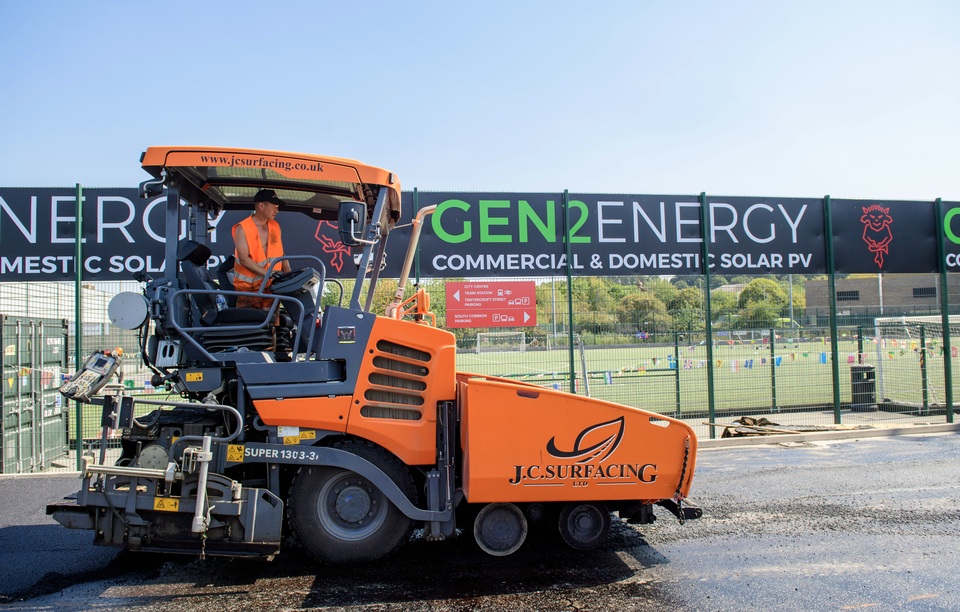 A man operates a machine to resurface a path