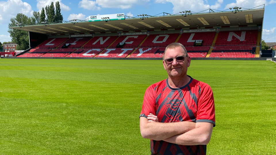 Graeme Power stands with his arms crossed in front of the GBM Stand at the LNER Stadium.