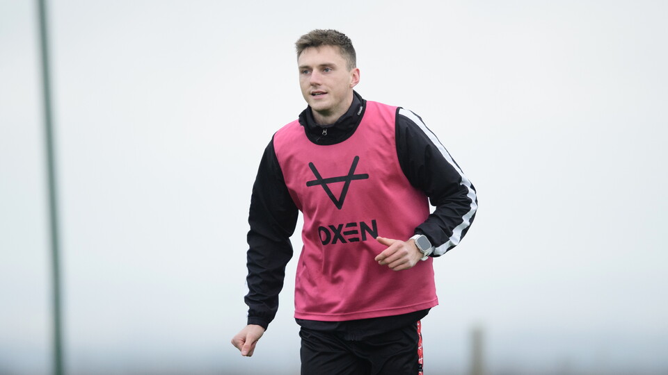 Hayden Cann during training. He is wearing a pink bib over a black jacket.