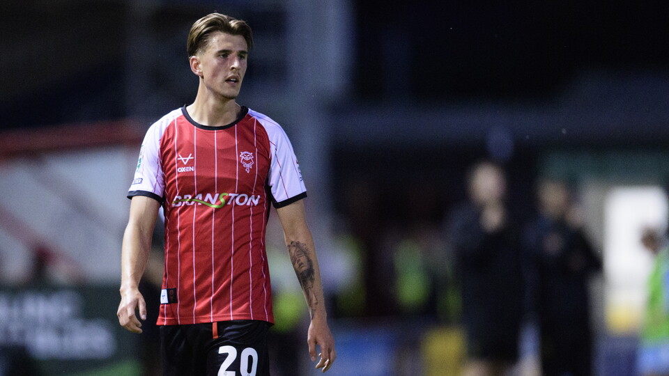 Jay Benn pictured during a football match, wearing a red  shirt and black shorts. 