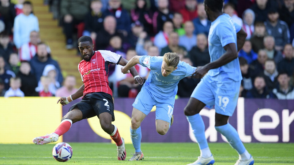 Tendayi Darikwa passes the ball with his right foot. He is challenged by a Leyton Orient player.