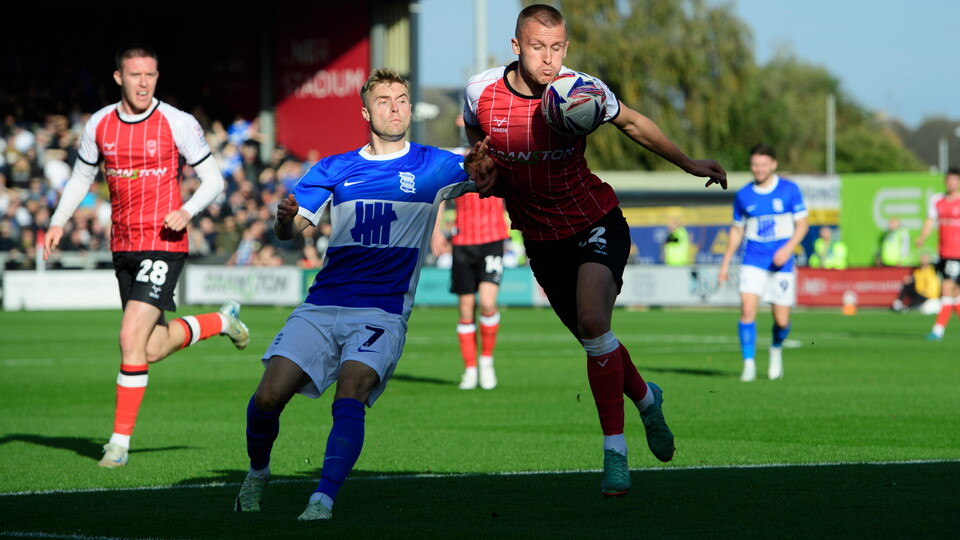 Lincoln City player Tom Hamer challenges for the ball with a Birmingham City player.