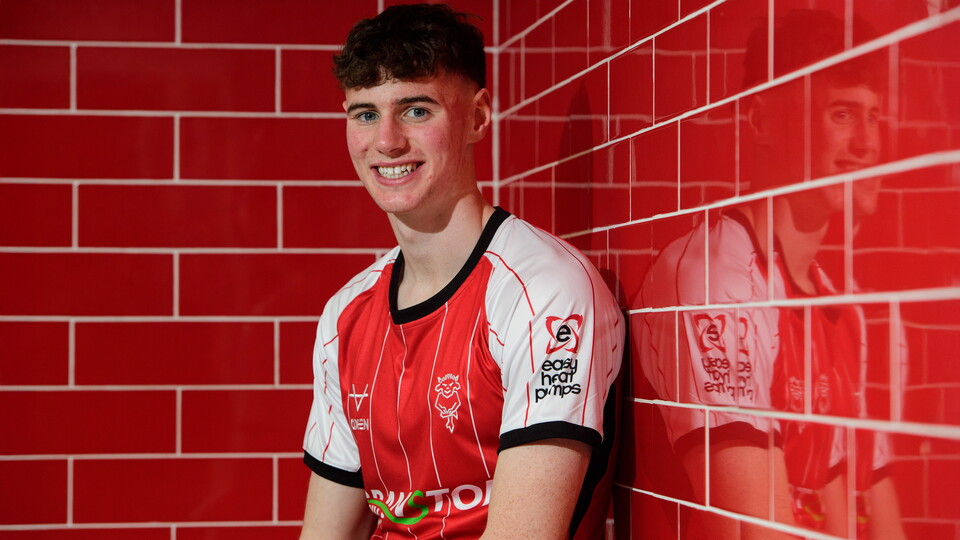 Joe Gardner sits in a changing room. He is wearing a red and white football top.