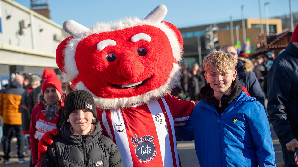 Poacher the Imp poses with two supporters in the University of Lincoln fan village