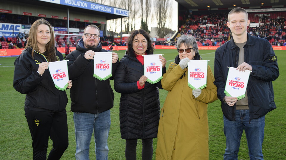 Five people stand in a line holding up pennants which read "EFL Community Hero"