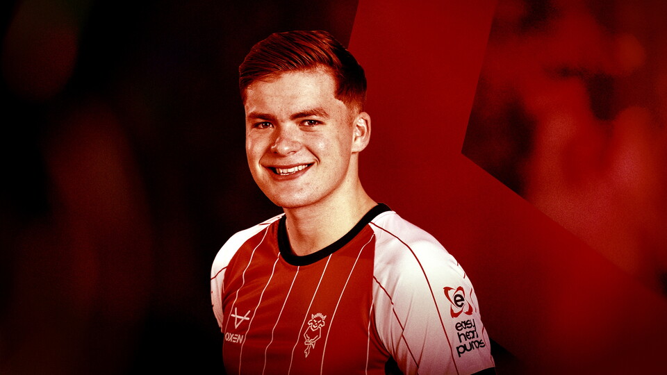 Freddie Draper smiles at the camera in a photo. There is a red and white graphic background.