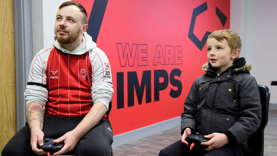 A man and a boy play video games in Poacher's Den