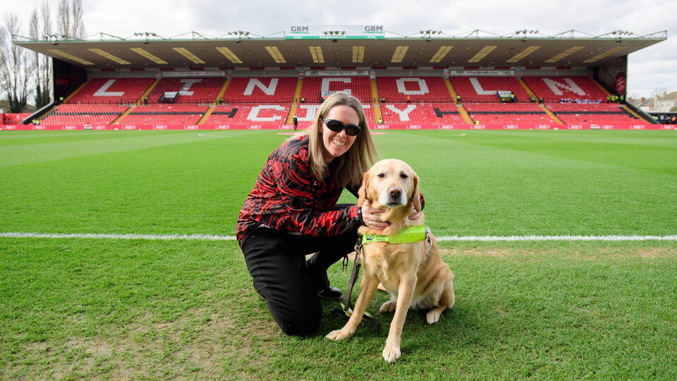 A woman with her guide dog at LNER Stadium 