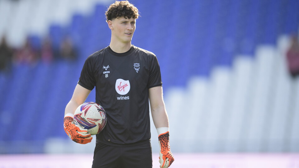 Jamie Pardington stands holding a football. He is wearing all-black training kit.