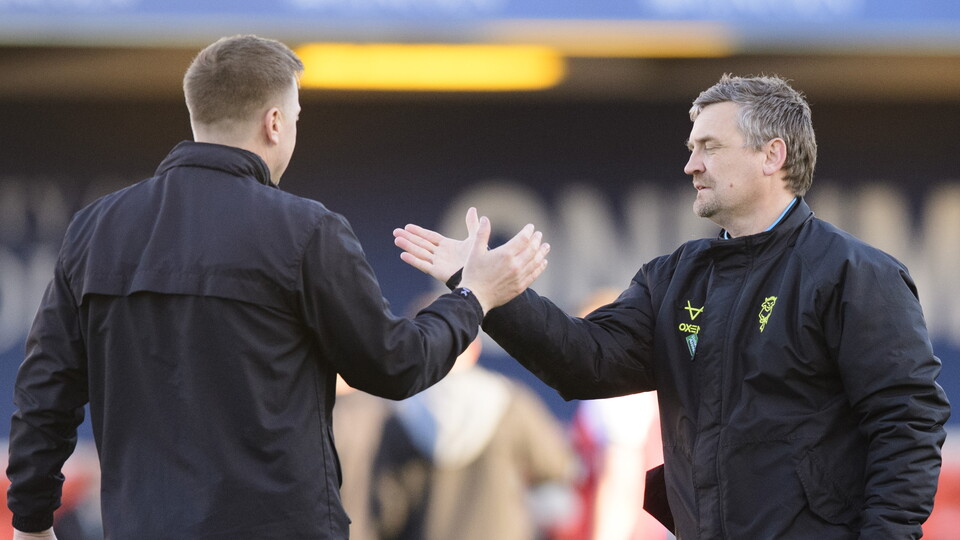 Two mean wearing all-black coats high five each other