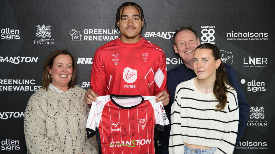 Jovon Makama holds a shirt while stood with three other people.