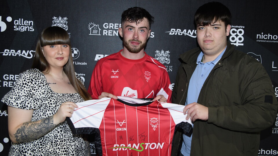Sean Roughan and sponsors hold up a signed shirt