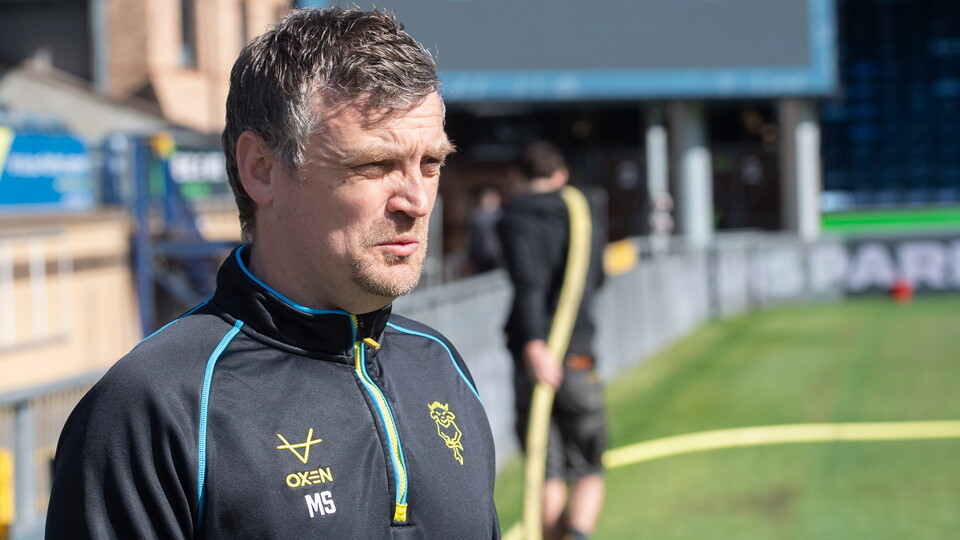 Michael Skubala stands by the side of a football pitch