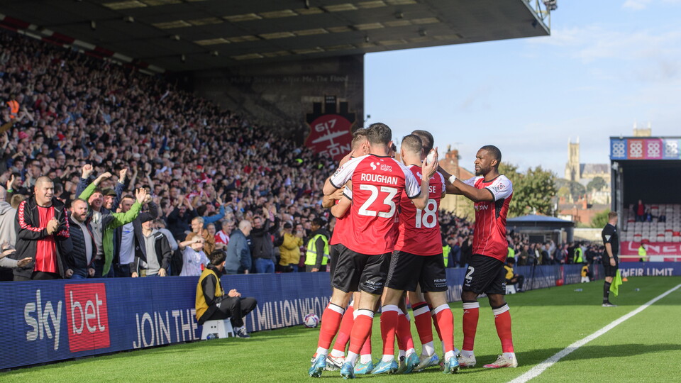Lincoln City players celebrate after scoring a goal