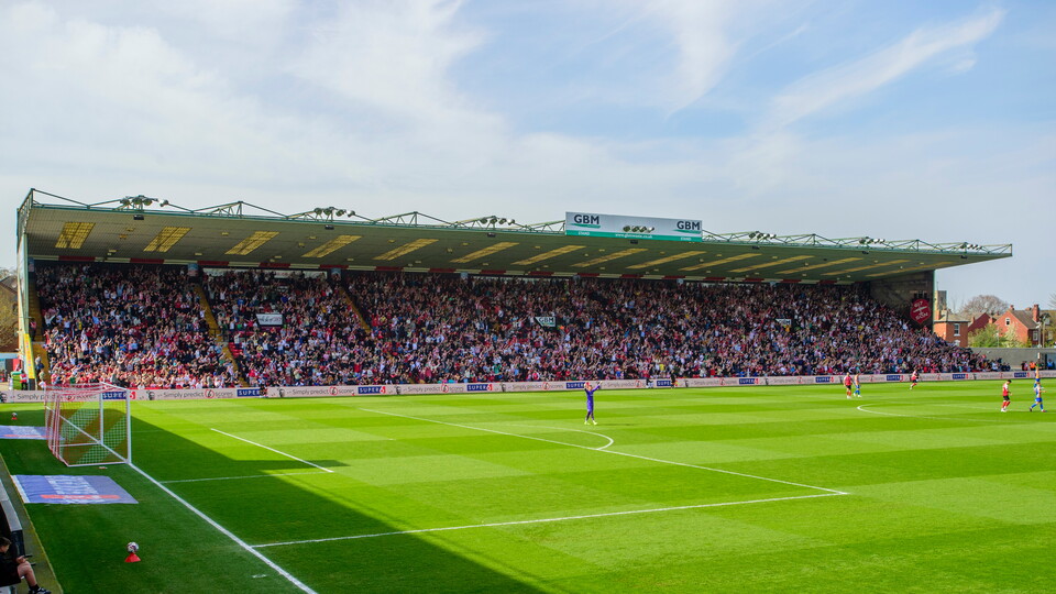 A full stand with spectators in front of a football pitch