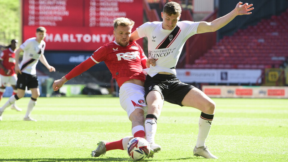 Two footballers try to get to the ball