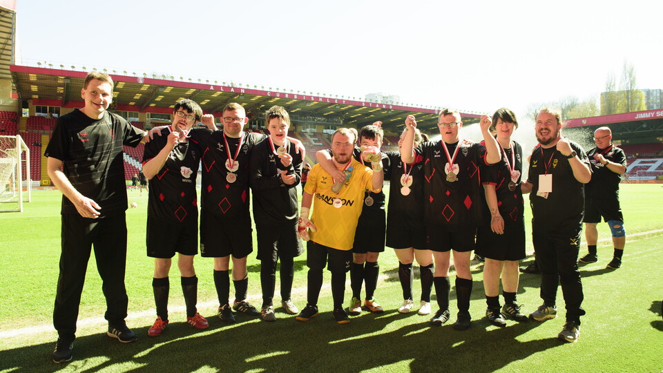 A group of people pose for a celebratory photo. They are all wearing black.