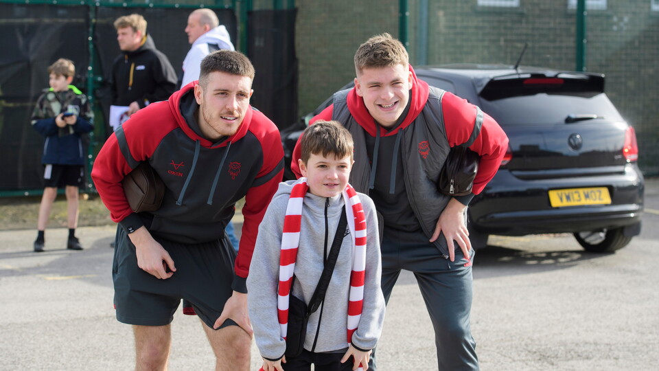 Two adult men pose for a photo with a young boy