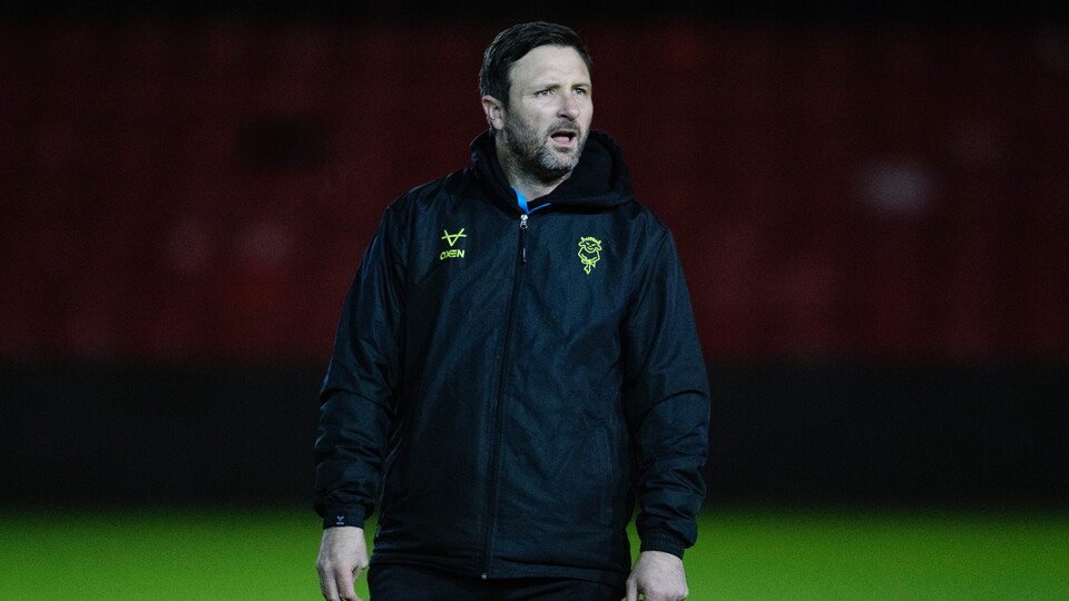 Sam Tillen, head coach of Lincoln City U18, looks on as his team warms up at the LNER Stadium