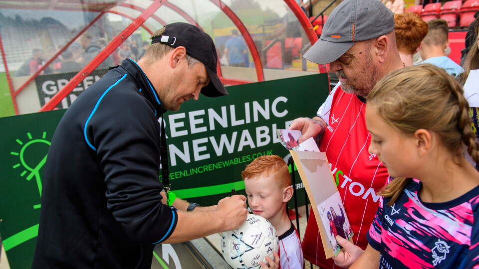 Michael Skubala, head coach of Lincoln City signs an autograph for a fan during an open training session at LNER Stadium, Lincoln, Lincolnshire.