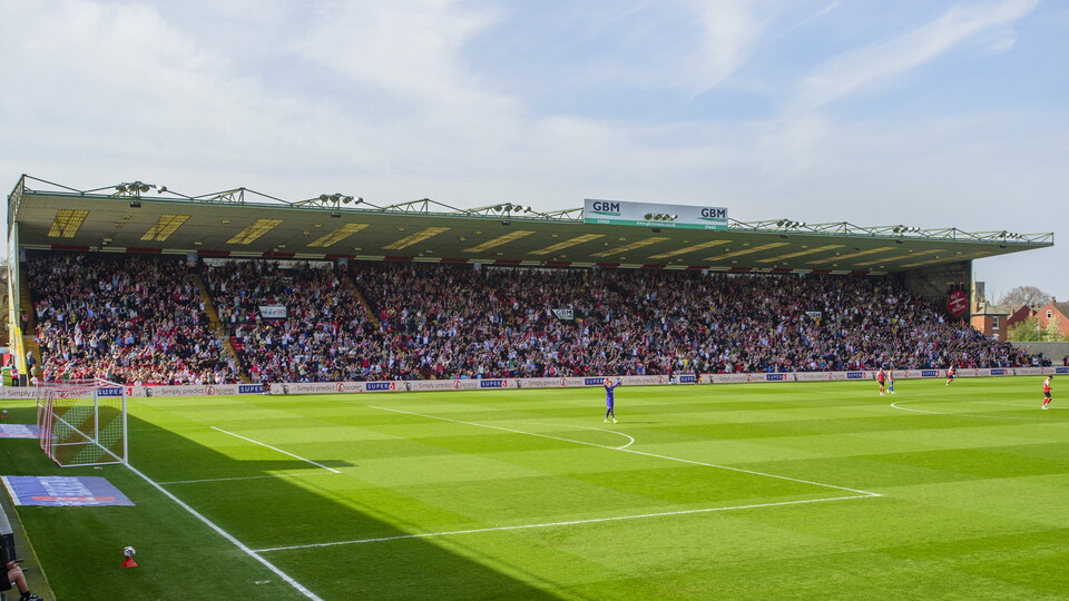 The GBM Stand at the LNER Stadium is full of fans on a sunny day.