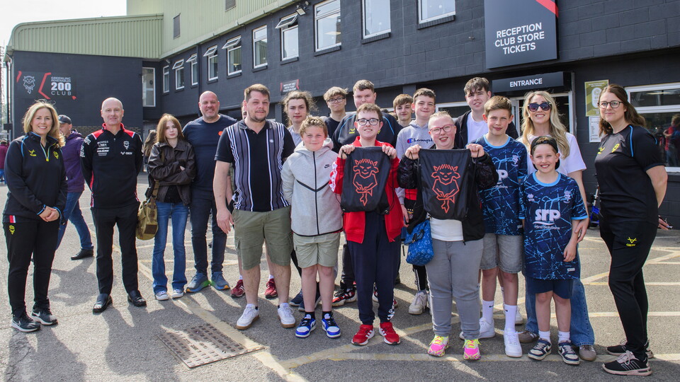 A group of people pose in front of the LNER Stadium