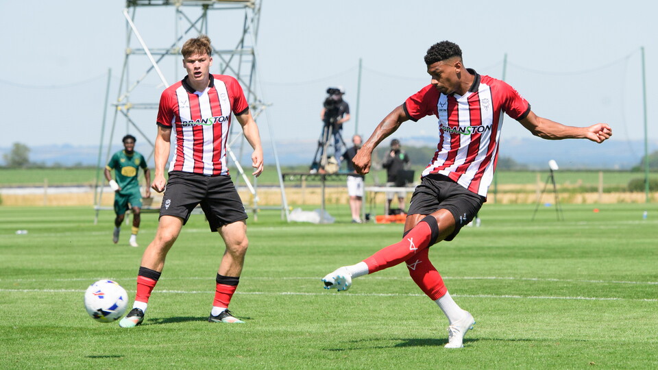 Reeco Hackett kicks a football with his left foot to score.
