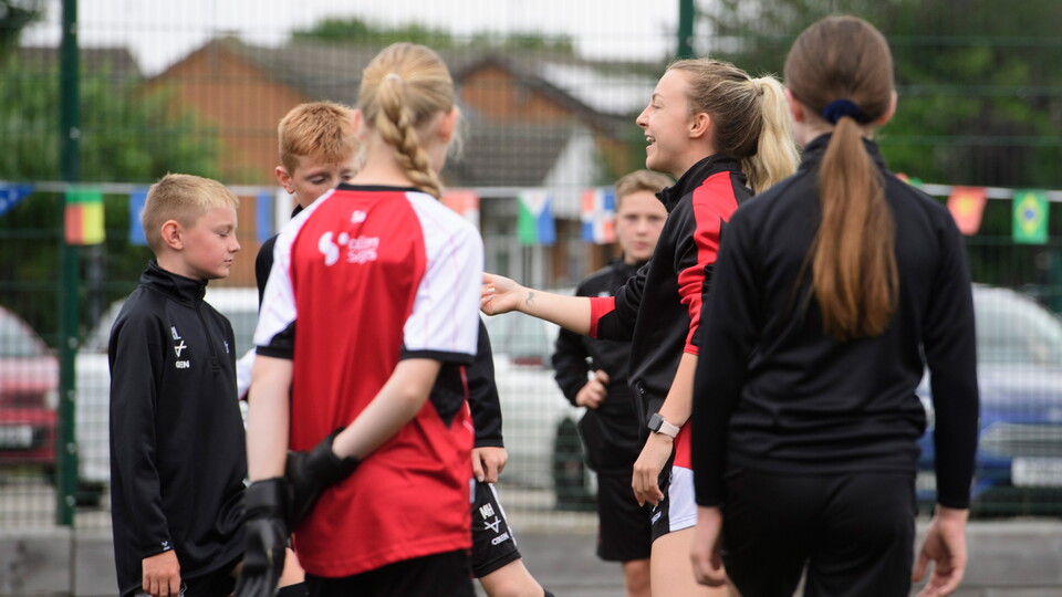Children listen to a coach during a football training session
