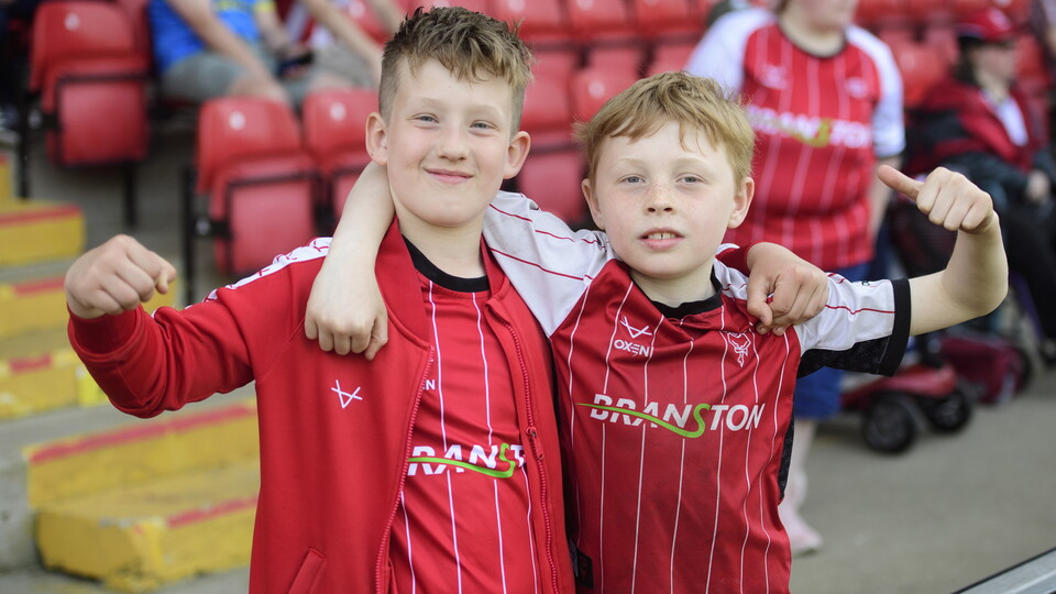 Two children in red Lincoln City tops pose for the camera