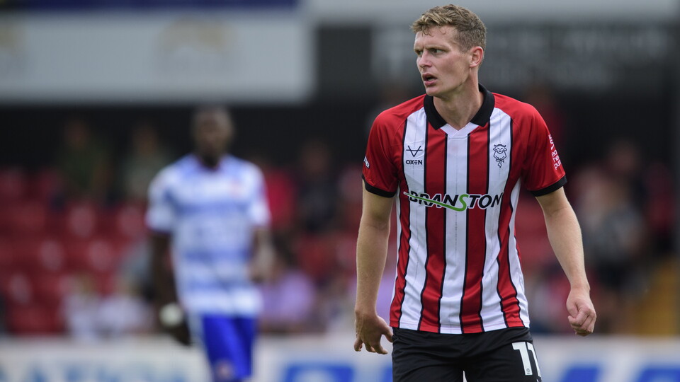 Ethan Hamilton stands during a football match. He is wearing a top with red and white stripes