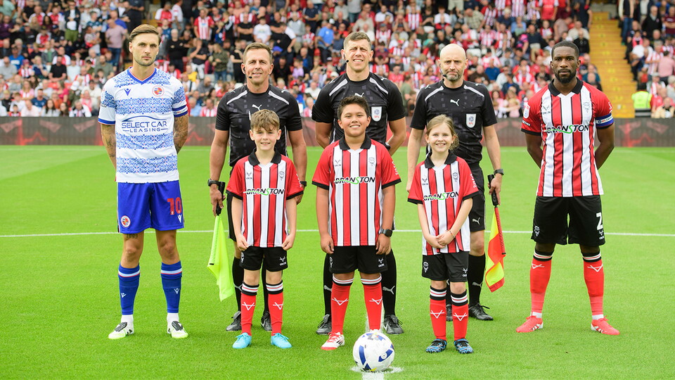 Mascots line up on the pitch before a Lincoln City home game.