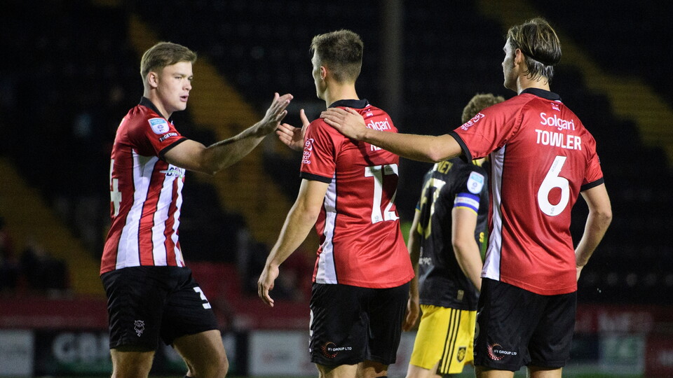 Erik Ring of Lincoln City, centre, celebrates scoring his side's second goal with team-mates Freddie Draper, left, and Ryley Towler, right during the Vertu Trophy Northern Section group D match between Lincoln City and Manchester United U21 at LNER Stadium, Lincoln.