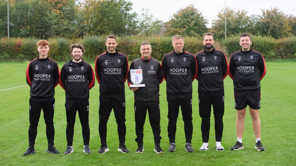 The Lincoln City coaching staff pose with the Sky Bet League One Manager of the Month trophy
