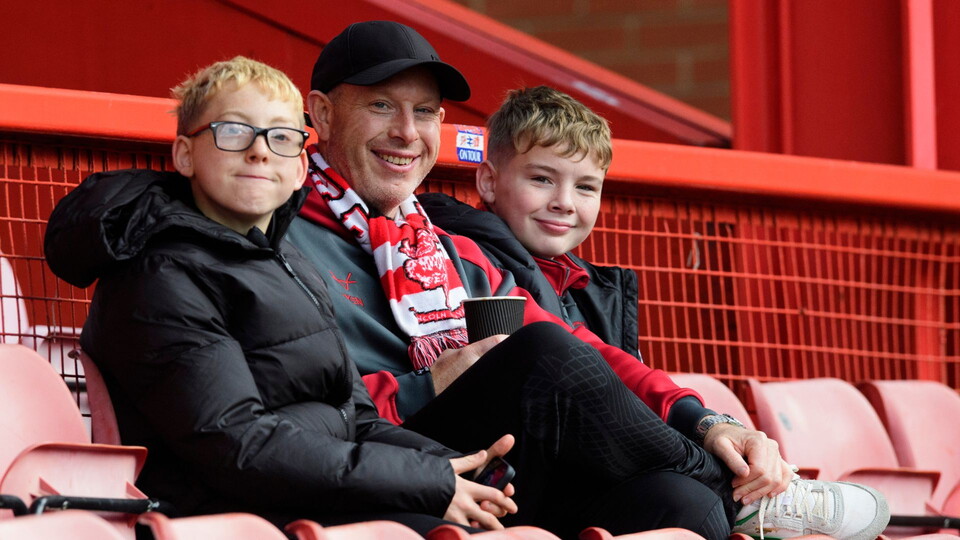A man sits with two boys either side of him. They are all looking at the camera.