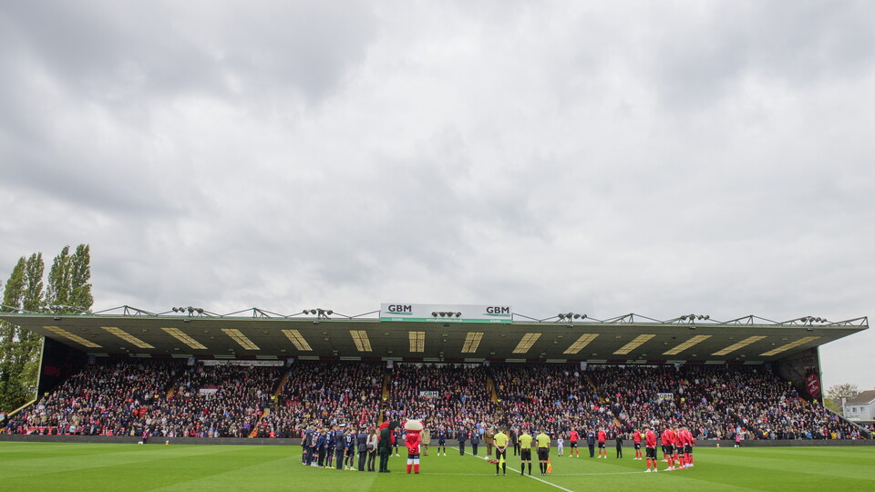 Footballers stand on a pitch