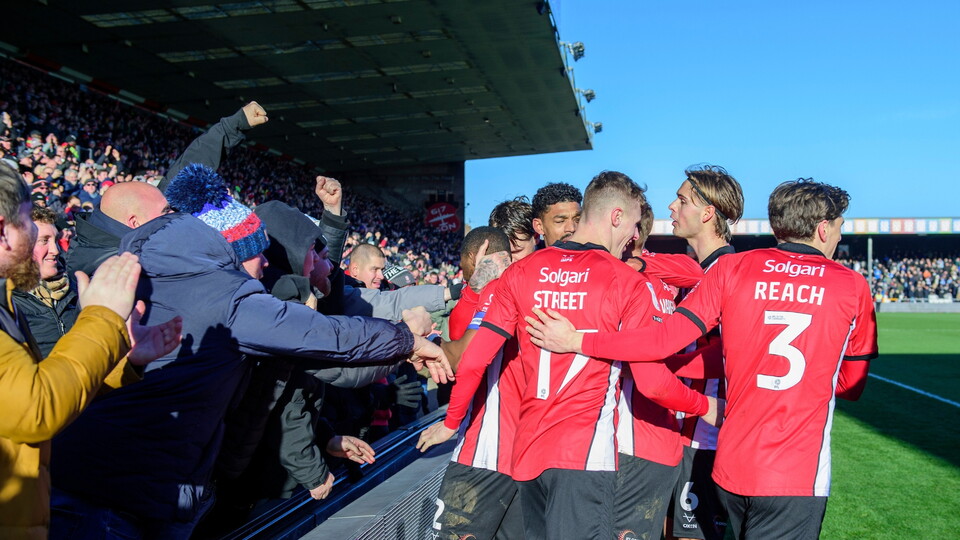 Tendayi Darikwa of Lincoln City celebrates scoring his side's third goal with team-mates and fans during the EFL Sky Bet League One match between Lincoln City and Peterborough United at LNER Stadium, Lincoln.