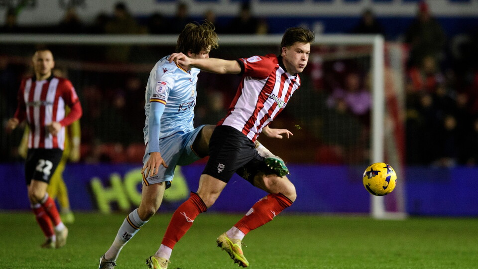 Freddie Draper of Lincoln City vies for possession with Tommy Leigh of Bradford City during the EFL Sky Bet League One match between Lincoln City and Bradford City at LNER Stadium, Lincoln.