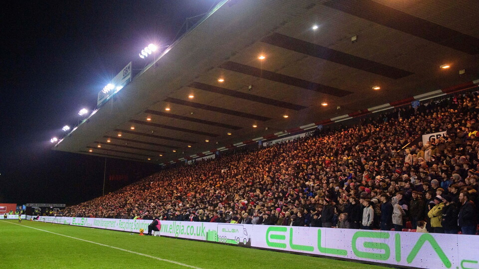 Packed football stadium stands under bright lights at night.
