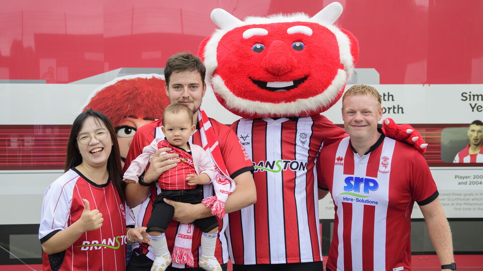 Poacher the Imp poses with a family of four people including a baby.