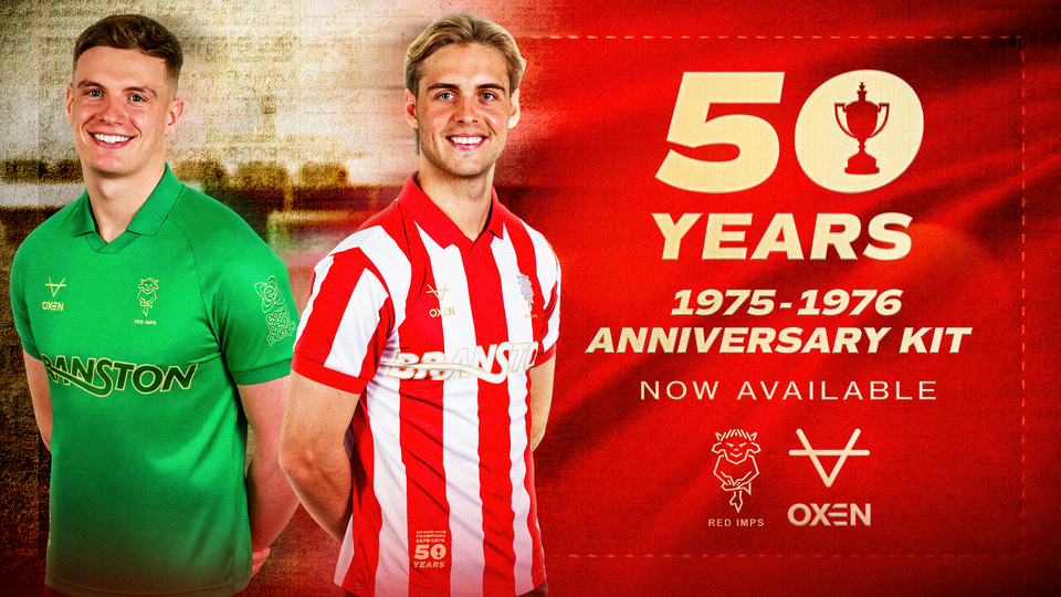 Two men pose in retro football shirts. One is a green goalkeeper top, the other is a red and white striped top.