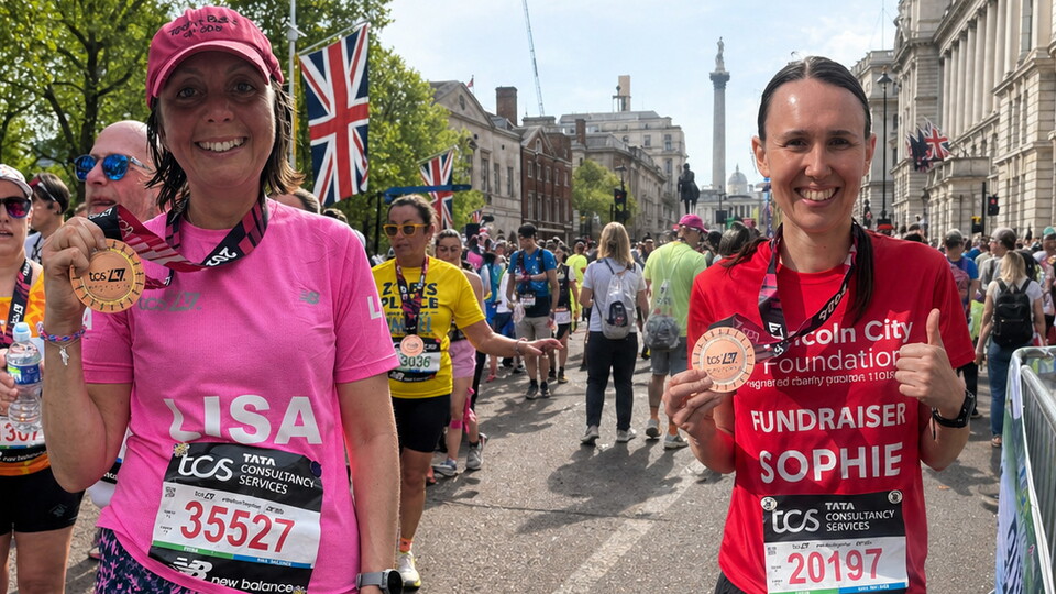 Two women pose with medals after completing the London Marathon