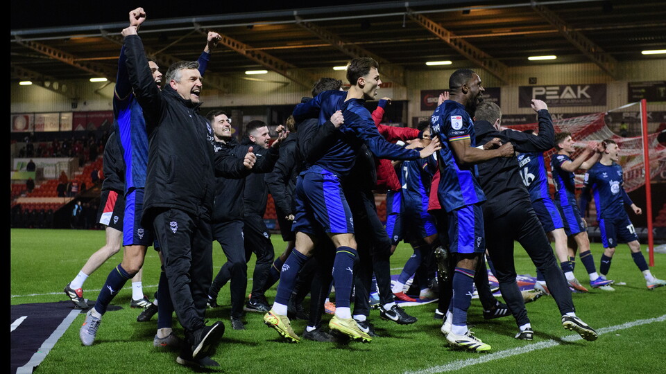 Coaches and players of Lincoln City celebrate after their win at Doncaster