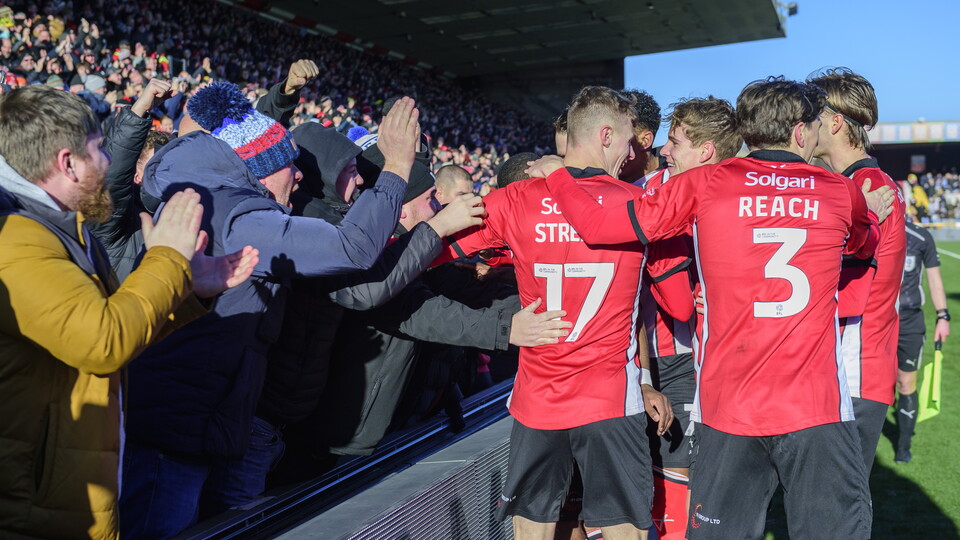 Lincoln City players celebrate a goal with fans