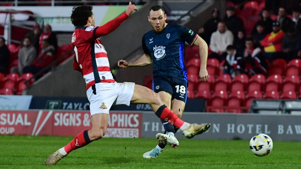Ben House, wearing all blue football top, kicks the ball to score against Doncaster Rovers.