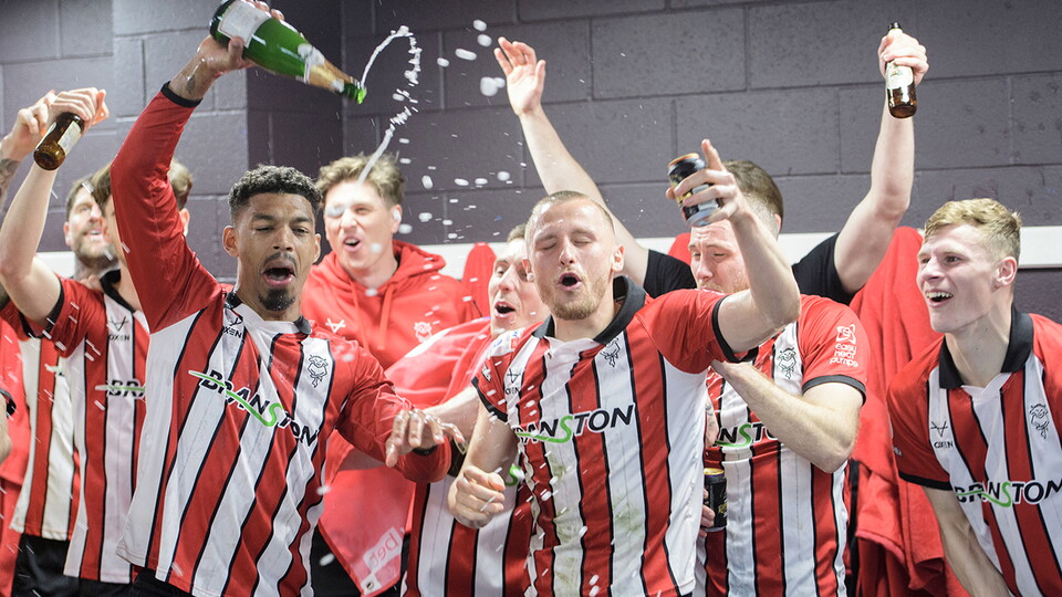 Lincoln's players celebrate promotion in the changing room at Reading