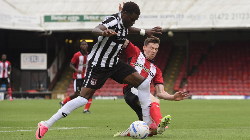 Conor McGrandles tackles a Grimsby Town player